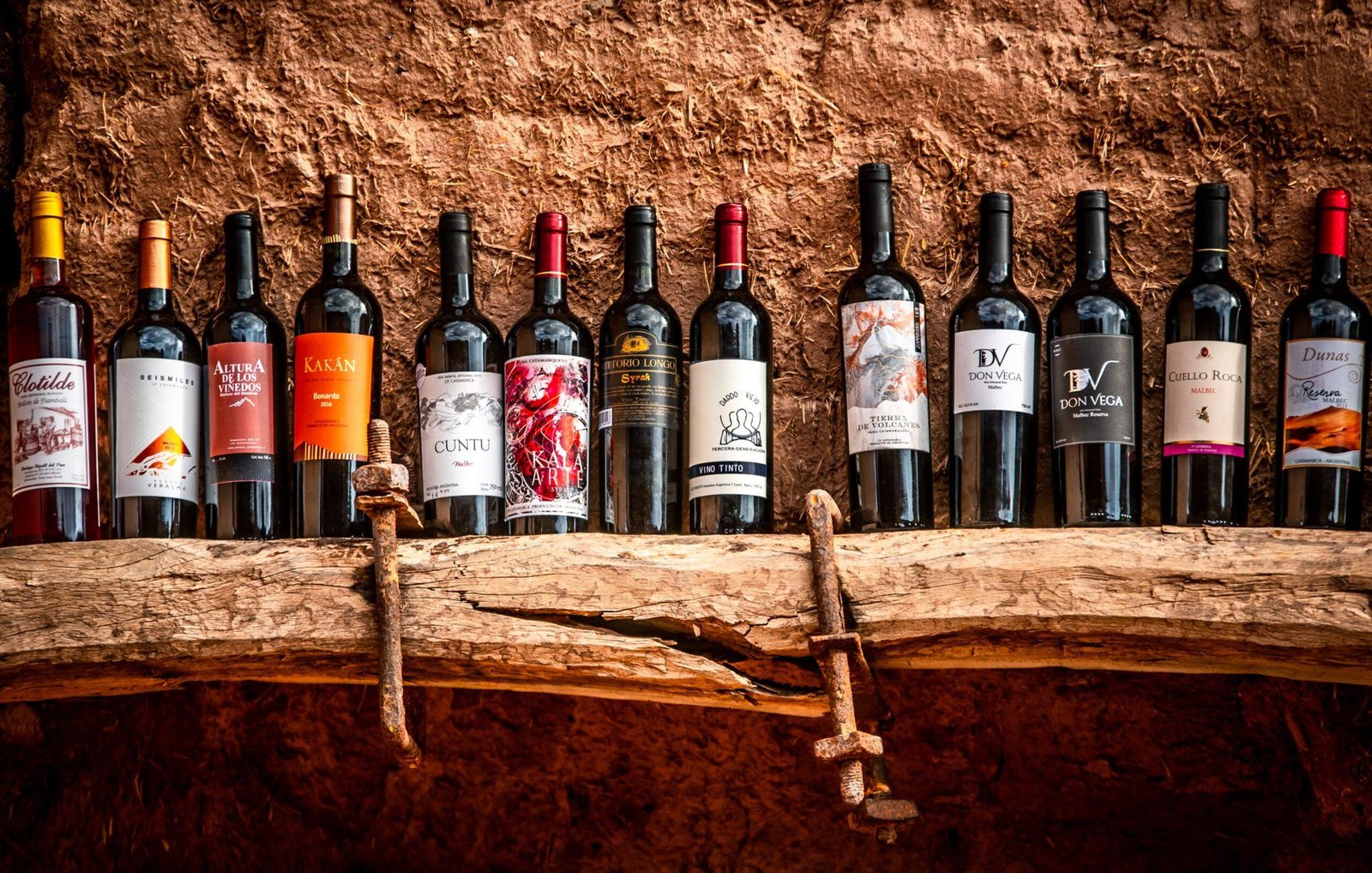 Botellas de los vinos de Tinogasta sobre una pared de adobe